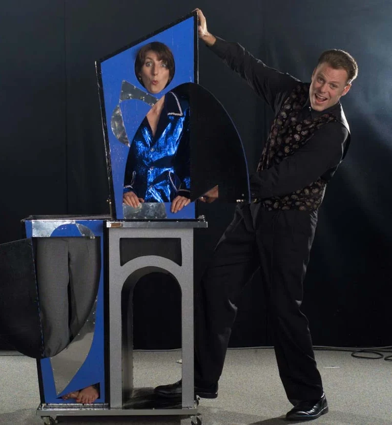 Holiday party magician Brock Edwards performing the Modern Art illusion with his assistant at a corporate holiday party show